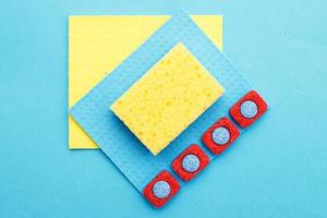 capsules for dishwashers, kitchen rags and sponges on a blue background. flat lay photo