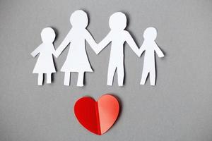 Happy paper cut family holding hands on gray background with red heart. photo