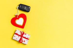 Top view of gift box, car key and wooden heart on colorful background. Luxury present for Valentine's day photo