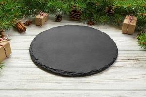 Perspective view. Empty black slate plate on wooden christmas background. holiday dinner dish concept with new year decor photo