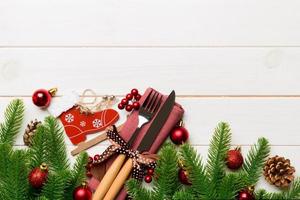 Top view of christmas decorations on wooden background. Fork and knife on napkin tied up with ribbon and empty space for your design. New year pattern concept photo