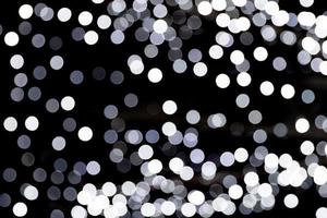 Abstract glitter sparkle bokeh defocused on black background. many round light on background photo