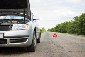 triángulo rojo de un coche en la carretera. triángulo de advertencia de coche en la carretera contra la ciudad por la noche. foto