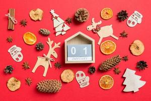 vista superior del calendario, fondo rojo decorado con juguetes festivos y símbolos navideños renos y árboles de año nuevo. el primero de enero. concepto de vacaciones foto