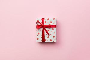 Background with gift box and hearts on rose Background. Top view with copy space for text photo