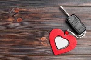 Top view of car key and heart as a present for Valentine's day on wooden background. Romance concept with copy space photo