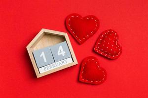 Top view of wooden calendar and textile hearts on colorful background. The fourteenth of February. Valentine's day concept photo