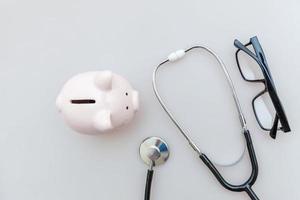 Medicine doctor equipment stethoscope or phonendoscope piggy bank glasses isolated on white background photo