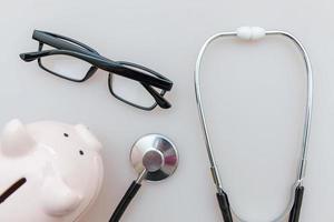 Medicine doctor equipment stethoscope or phonendoscope piggy bank glasses isolated on white background photo