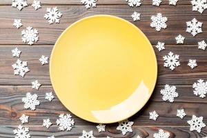 Top view of empty plate surrounded with snowflakes on wooden background. New Year dinner concept photo