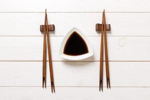 Soy sauce with chopsticks on white wooden table background photo