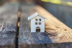 casa modelo de juguete blanco en miniatura con fondo de madera. aldea ecológica, fondo ambiental abstracto foto