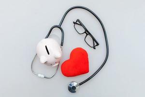 Equipo médico de medicina estetoscopio o fonendoscopio hucha gafas y corazón rojo aislado sobre fondo blanco. foto