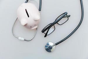 Medicine doctor equipment stethoscope or phonendoscope piggy bank glasses isolated on white background photo