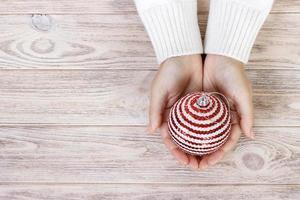 Christmas concept with hand and white ball - christmas tree toy. White round christmas ball in female hand. Wooden Background photo