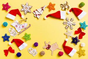 Top view of Christmas decorations and Santa hats on yellow background. Happy holiday concept with copy space photo