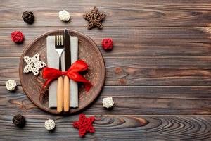 Holiday composition of Christmas dinner on wooden background. Top view of plate, utensil and festive decorations. New Year Advent concept with copy space photo