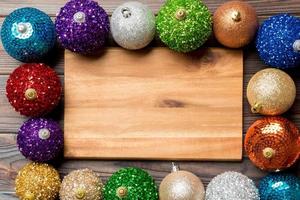 Top view of empty plate surrounded with colorful baubles on wooden background. New Year decorations. Christmas Eve concept photo