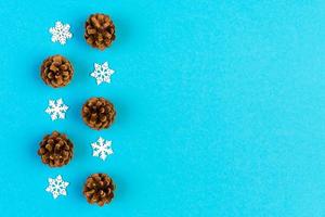 Top view of New Year ornament made of white snowflakes and pine cones on colorful background. Winter holiday concept with empty space for your design photo