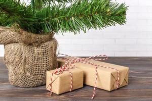 Different New Year's gifts wrapped in wrapping paper under the Christmas tree branch photo