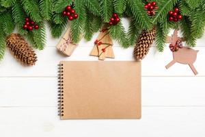 Top view of fir tree, New Year decorations and notebook on wooden background. Christmas concept with copy space photo