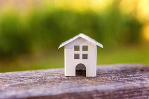 casa modelo de juguete blanco en miniatura con fondo de madera cerca de fondo verde. aldea ecológica, antecedentes ambientales abstractos foto