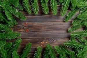 Top view of frame made of fir tree branches on wooden background. Christmas concept with empty space for your design photo