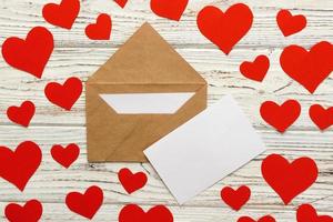 carta para el día de san valentín. sobre de carta de amor con corazones rojos sobre fondo de madera foto