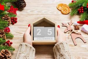Top view of female hands holding a calendar on wooden background. The twenty fifth of December. Holiday decorations. Christmas concept photo