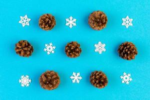 Top view of holiday composition made of pine cones and white snowflakes on colorful background. Winter time and Christmas concept with copy space photo