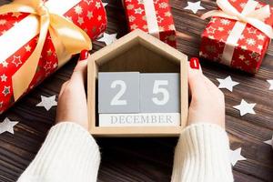 Top view of female hands holding a calendar on wooden background. The twenty fifth of December. Holiday decorations. Christmas concept photo