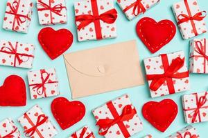 Top view of colorful valentine background made of craft envelope, gift boxes and red textile hearts. Valentine's Day concept photo