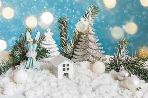 Fondo abstracto de Navidad de Adviento. casa modelo de juguete y adornos de invierno sobre fondo azul con nieve y luces de guirnalda desenfocadas. concepto de navidad con familia en casa. foto