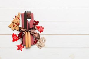 Top view of fork and knife tied up with ribbon on napkin on wooden background. Christmas decorations and New Year tree. Happy holiday concept with empty space for your design photo
