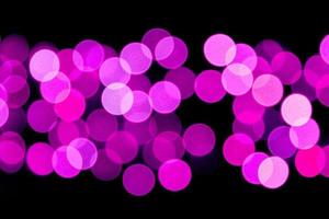 Unfocused abstract purple bokeh on black background. defocused and blurred many round light photo