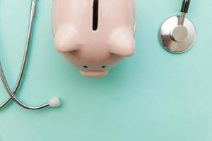 Medicine doctor equipment stethoscope or phonendoscope and piggy bank isolated on trendy pastel blue background photo