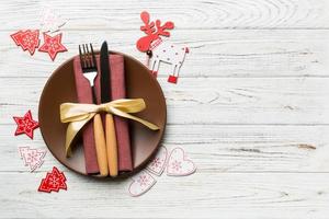 Top view of plate, fork and knife served on Christmas decorated wooden background. New Year Eve concept with copy space photo