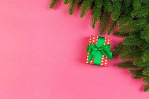 Top view of fir tree branches and gift box on colorful background. Christmas time concept with empty space for your design photo