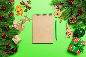 Top view of notebook on green background made of Christmas decorations. New Year time concept photo