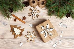 gift box in craft paper with Christmas decoration, twine rope, concept background, top view on wood table surface. Christmas ornaments and presents border with snowflakes and stars photo