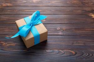 paper gift box with blue ribbon on dark wood background. top view with copy space photo