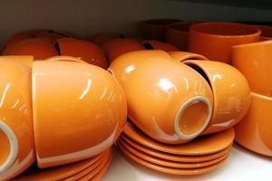 Bright orange cup standing on white shelf. Clean ordered dishes in store photo