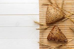 Several small multi grain triangular shaped bread sprinkled with whole sunflower seeds, flax and sesame seeds and wheat and barley spikes photo