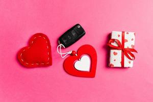 Top view of gift box, car key, wooden and textile heart on colorful background. Luxury present for Valentine's day photo