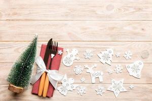 Top view of fork and knife tied up with ribbon on napkin on wooden background. Christmas decorations and New Year tree. Happy holiday concept with empty space for your design photo