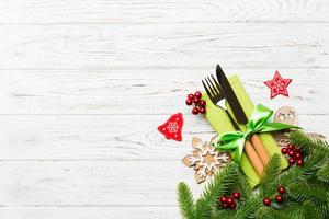 Top view of christmas decorations on wooden background. Fork and knife on napkin tied up with ribbon and empty space for your design. New year pattern concept photo