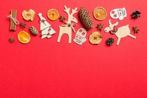 Top view of red background decorated with festive toys and Christmas symbols reindeers and New Year trees. Holiday concept with copy space photo