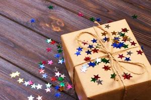 Gift box with star. Creative concept with festive decor on black background. Confetti stars, red, yellow with gift box. Explosion of confetti photo