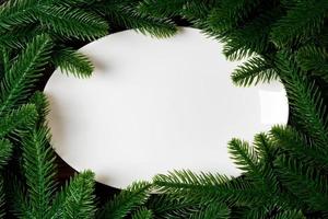 Top view of white plate surrounded with fir tree branches. Christmas dinner concept with copy space photo