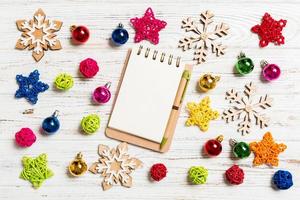 Top view of notebook on wooden background made of Christmas decorations. New Year concept photo
